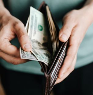 Close-up of hands holding a wallet with cash, depicting financial management.